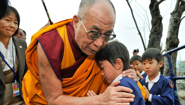 Sa Sainteté le Dalaï Lama réconfortant un jeune survivant lors de sa visite dans la région de Sendai au Japon, dévastée par un tsunami, le 5 novembre 2011 (photo de Tenzin Choejor, OHHDL)
