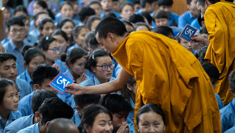 Des assistants se déplaçent parmi le public avec des objets rituels alors que Sa Sainteté le Dalaï-Lama donne la permission de Manjoushri blanc le dernier jour de ses enseignements pour les jeunes étudiants tibétains au temple tibétain principal à Dharamsala, Inde, le 8 juin 2018. Photo de Tenzin Choejor