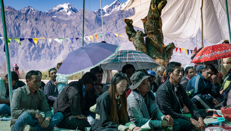 Des montagnes s'élèvent de la vallée de Nubra à l'arrière-plan alors que les membres du public écoutent l'enseignement de Sa Sainteté le Dalaï-Lama au monastère de Samstanling à Sumur, dans la vallée de Nubra, Ladakh, Inde, le 16 juillet 2018. Photo de Tenzin Choejor